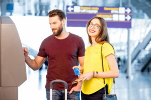 Young couple withdrawing money using ATM at the airport during their travel