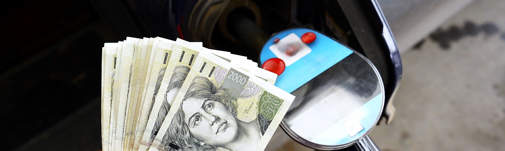 Banknoty korony czeskiej  obok dystrybutora paliwa