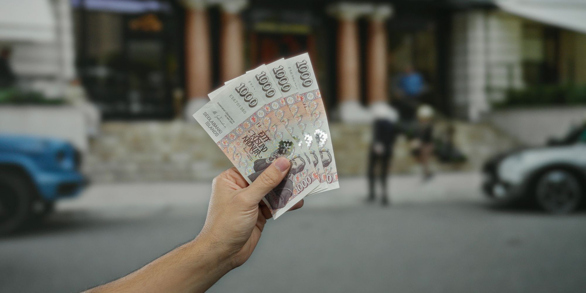 Banknoty korony szwedzkiej w ręce, w tle miasto