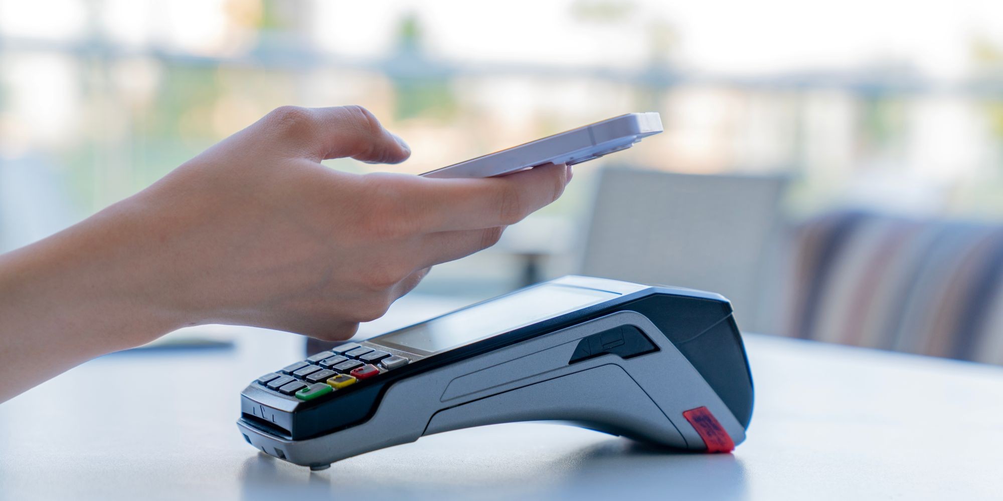 Dłoń z telefonem przy terminalu płatniczym