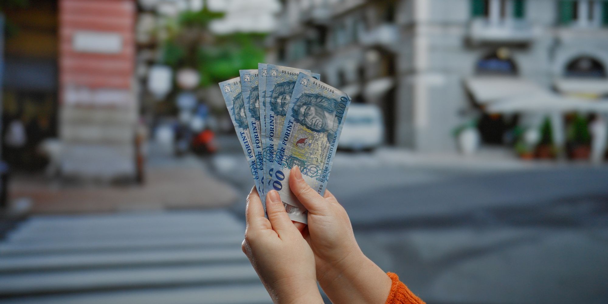 Forint węgierski, banknoty w dłoni na tle ulicy.