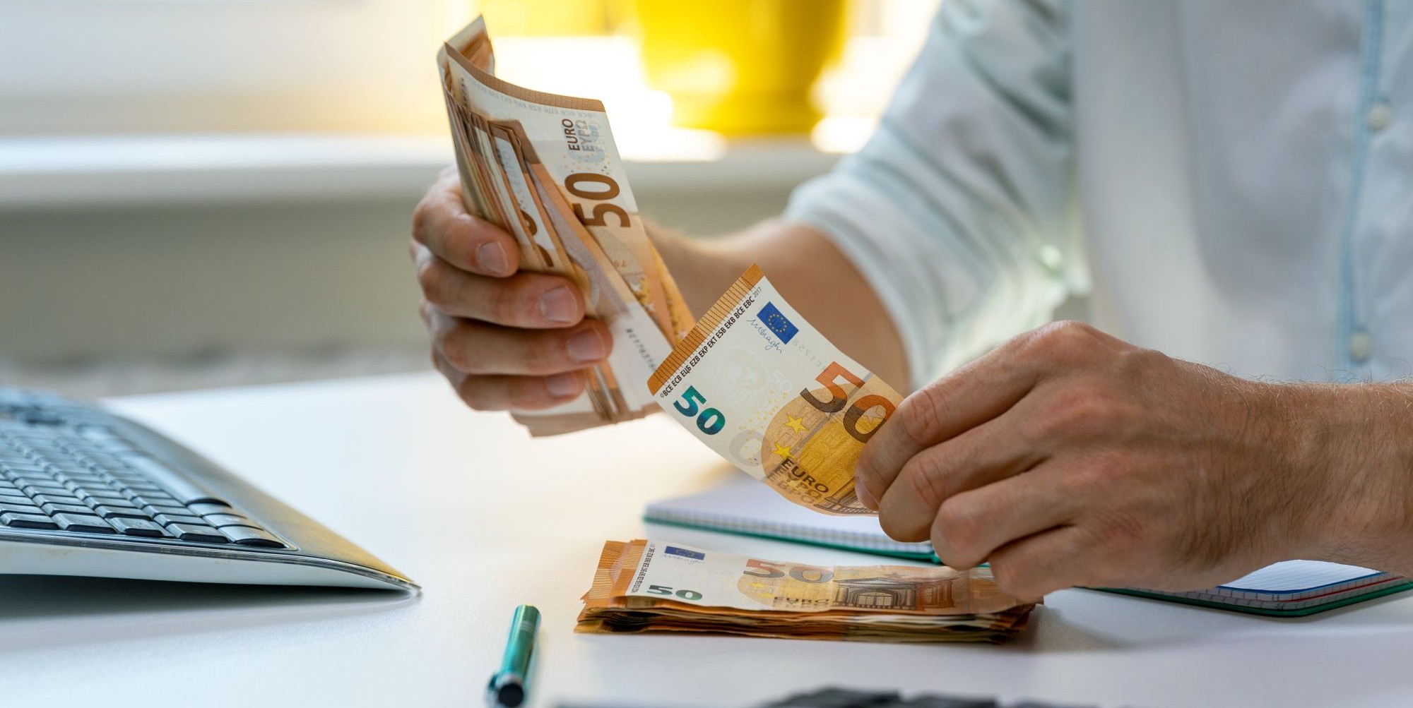 Mężczyzna przy biurku przelicza banknoty euro