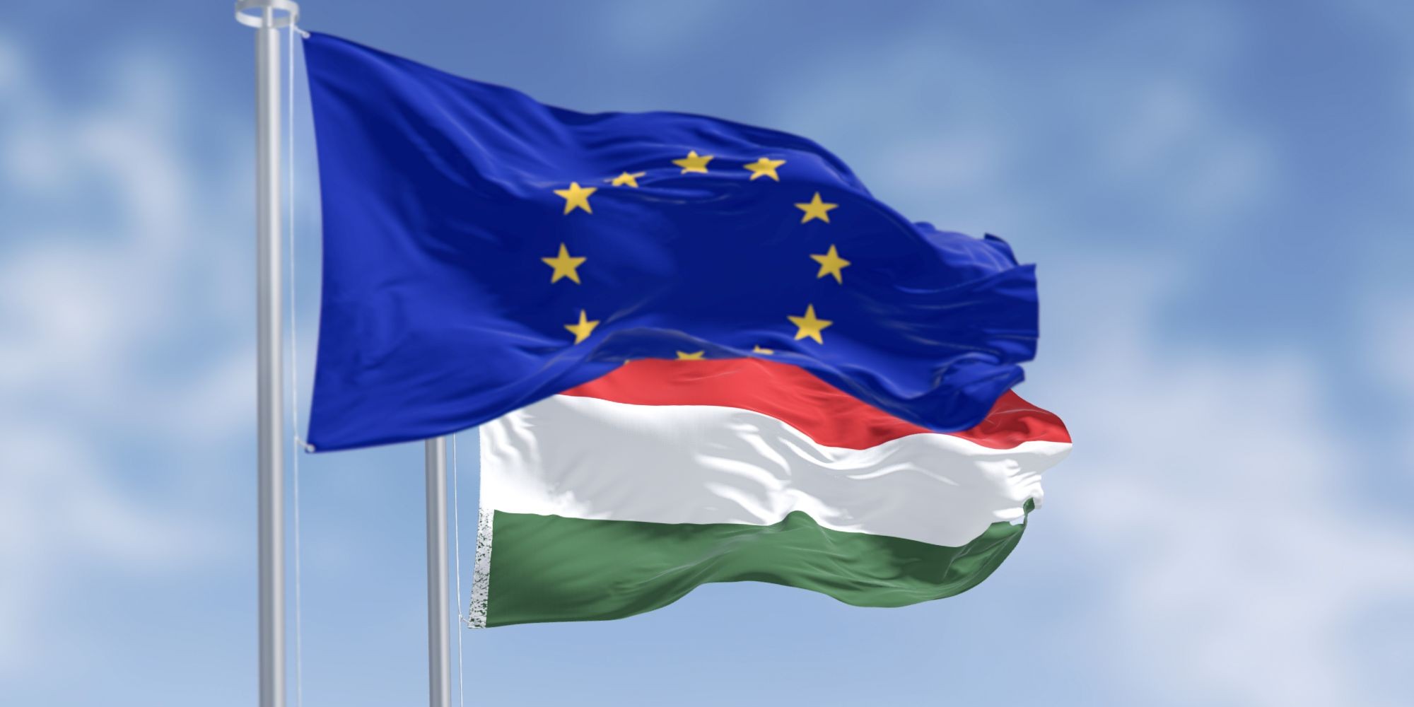 Flagi Węgier i Unii Europejskiej powiewające na masztach